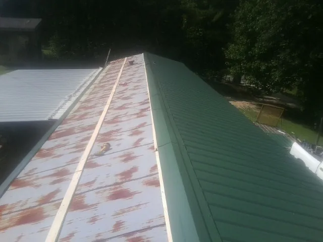 Old rusted panels beside newly installed green metal roofing — Wind Damage Roof Repair by Roofing Brothers in Dewitt